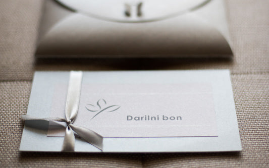 Fizični darilni bon Studio Ping v kuverti ali darilni embalaži, pripravljen za pošiljanje po pošti, s poudarkom na elegantni in osebni predstavitvi darila.