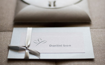 Fizični darilni bon Studio Ping v kuverti ali darilni embalaži, pripravljen za pošiljanje po pošti, s poudarkom na elegantni in osebni predstavitvi darila.